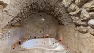 a bath tub in a stone room with candles around it at HEMDAT NEFESH in Safed