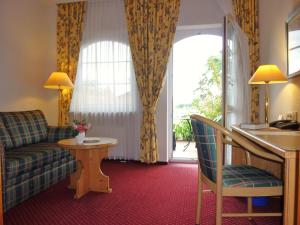 um quarto de hotel com um sofá e uma mesa em Landhaus Müritzgarten Hotel garni em Röbel