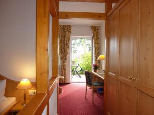 um corredor de um quarto de hotel com uma secretária e uma porta em Landhaus Müritzgarten Hotel garni em Röbel