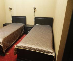 a room with two beds and two night stands at DzhaNat Hotel in Sukhum