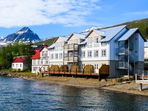 a row of houses next to a river with a mountain at Fosshotel Eastfjords in Fáskrúðsfjörður