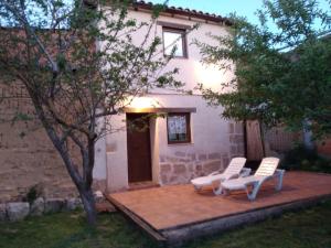 un patio con 2 sillas blancas y una casa en La casa de los abuelos lugar para disfrutar en Amusco