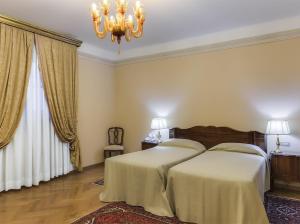1 Schlafzimmer mit 2 Betten und einem Kronleuchter in der Unterkunft Villa Fenaroli Palace Hotel in Rezzato