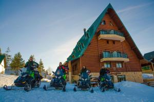 een groep mensen op sneeuwscooters voor een gebouw bij Hotel Polar Star in Žabljak