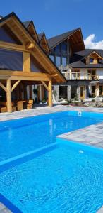 a large blue swimming pool in front of a house at Willa Zaolzie in Istebna