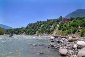 a boat on a river with mountains in the background at Regenta Inn by Riverside Manali in Manāli