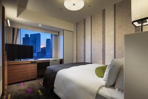 a hotel room with a large bed and a television at Hotel Monterey Le Frere Osaka in Osaka