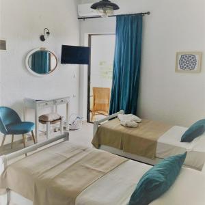 una camera con due letti, una sedia e uno specchio di Elounda George Studios a Eloúnda
