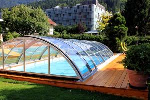 una piscina con una casa de cristal en una terraza en Gästehaus Steiner, en Tröpolach