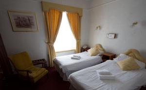 a hotel room with two beds and a chair at Union Hotel in Penzance
