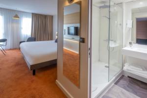 une chambre d'hôtel avec un lit et une douche dans l'établissement Mercure Rouen Centre Champ de Mars, à Rouen