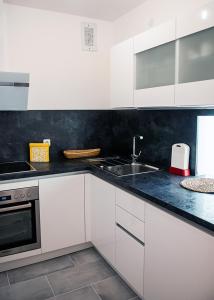 eine weiße Küche mit einer Spüle und einem Herd in der Unterkunft Apartment am Bahnhof in Salzburg