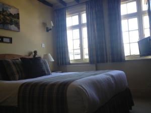 a bedroom with a bed and two windows at The Rock Inn in Bovey Tracey