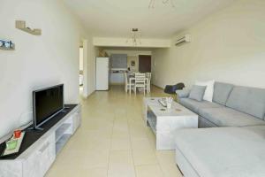 a living room with a couch and a flat screen tv at Nissi Martha Apartment in Ayia Napa