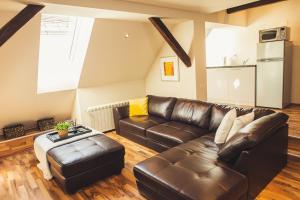 a living room with a leather couch and a table at SKOL apartments in Celje