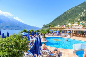 a beach filled with lots of blue umbrellas at Hotel San Pietro in Limone sul Garda