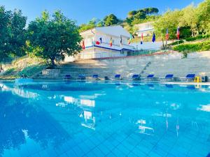 duży basen z krzesłami i budynek w obiekcie NaturaMare Apartments - Piscina Idromassaggio con Vista Mare Aperta fino alle ore 22-00 w mieście Capo Vaticano