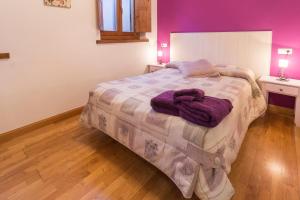 1 dormitorio con 1 cama grande, paredes moradas y suelo de madera. en apartamento AZKOITI ETXEA, en Ochagavía
