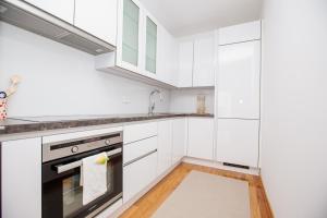 eine Küche mit weißen Schränken und einem schwarzen Backofen in der Unterkunft Bright 2-Bed Apartment Free Parking & WiFi - Walk to Old Town in Ljubljana