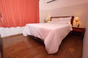 um quarto com uma cama grande com lençóis brancos e almofadas em Nena Suite Hotel em Franca