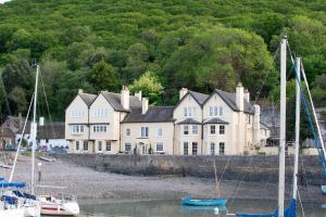 The Porlock Weir Hotel في بورلوك: بيت ابيض كبير وفيه قوارب في الماء