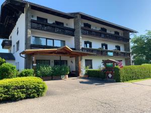 a large white building with a porch and bushes at Keutschacherhof in Keutschach am See