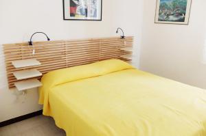 una camera con un letto giallo e due luci di Villetta Greta a Torre Lapillo