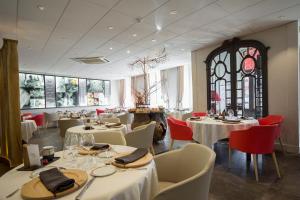 un restaurante con mesas y sillas blancas y una ventana en Hôtel de France, en Montmarault