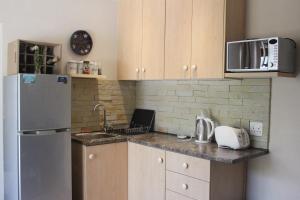 una cucina con lavello e frigorifero di Malachite Cottage a Kommetjie