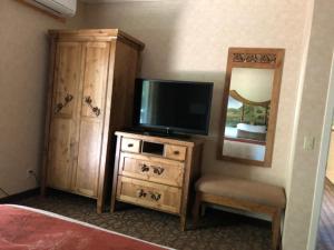 a bedroom with a television and a dresser with a mirror at El Bonita Motel in St. Helena