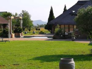 un parc avec un bâtiment et un baril dans l'herbe dans l'établissement Stone Hounds Lodge, à Magaliesburg