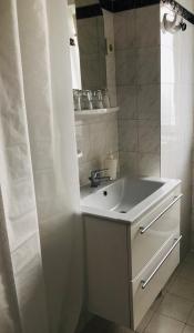 ein weißes Badezimmer mit einem Waschbecken und einem Spiegel in der Unterkunft Kis Gellért Guesthouse in Budapest