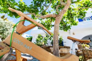 a wooden chair sitting next to a tree at Vincenzo Family Rooms in Tinos