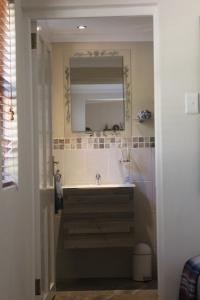 a bathroom with a sink and a mirror at Malachite Cottage in Kommetjie