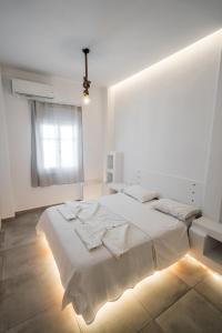 a white bedroom with a large bed and a window at Esmeralda Apartments in Apollonia