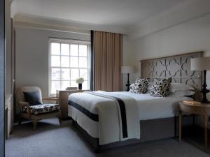a bedroom with a bed and a chair and a window at The Bloomsbury Hotel in London