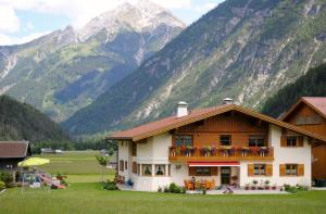 a house with a balcony with mountains in the background at Haus Gaby in Holzgau