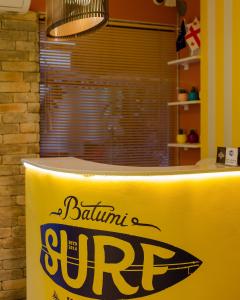 un mostrador amarillo con un cartel de surf. en Batumi Surf Hostel, en Batumi