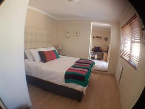 una camera da letto con un letto e uno specchio di Malachite Cottage a Kommetjie