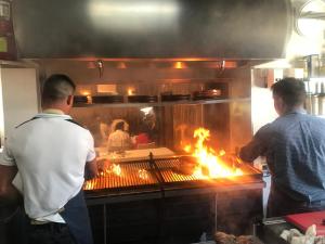 two men standing in a kitchen cooking on a grill at Hotel Rural Quercus Tierra in Garganta de los Montes
