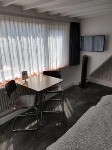 Cette chambre comprend une table, des chaises et des fenêtres. dans l'établissement Hoogland aan Zee, à Egmond aan Zee