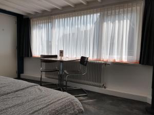 a bedroom with a table and two chairs in front of a window at Hoogland aan Zee in Egmond aan Zee