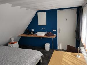 een slaapkamer met een wastafel en een blauwe muur bij Hoogland aan Zee in Egmond aan Zee