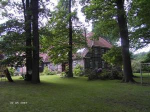 ein Haus mit einer Gruppe von Bäumen im Hof in der Unterkunft Ferienhof Wroge in Wietzendorf