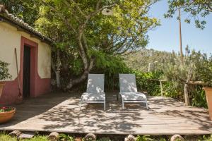 twee stoelen op een houten terras naast een huis bij Casa Da Muda in Ponta do Pargo
