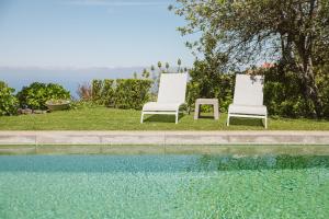 twee stoelen en een tafel naast een zwembad bij Casa Da Muda in Ponta do Pargo