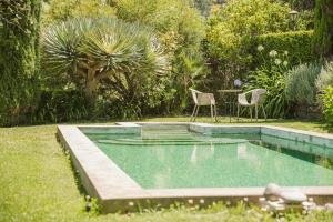 a pool in a yard with two chairs and a table at Casa Da Muda in Ponta do Pargo
