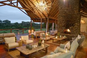 een grote woonkamer met een open haard en meubilair bij Lion Sands Narina Lodge in Sabi Sand Game Reserve