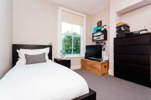 a bedroom with a white bed and a television at Veeve - Heaven in Highgate in London