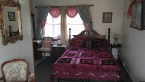a bedroom with a bed with a red comforter and a window at Midway Lodging in Cornish